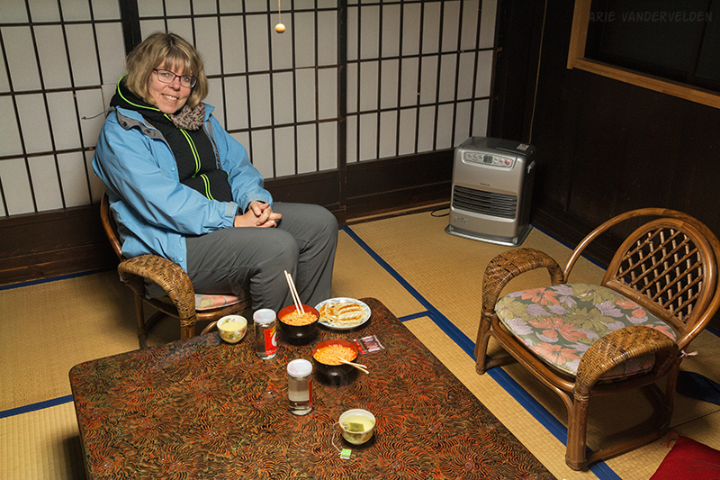 Dinner of ramen noodles, gyoza dumplings, sake in glass jars, and tea. Note the space heater in the corner.
